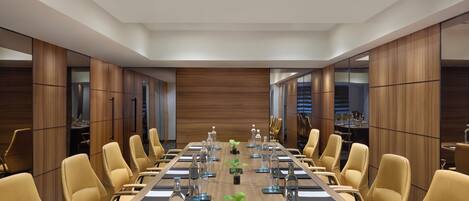 A conference room with a long table, yellow chairs, and wooden paneling.