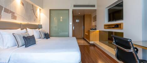 Una habitación de hotel moderna con una cama grande, un escritorio y un televisor.