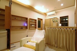 A room with a bed, a chair, a vanity with a mirror, shelves with decorative items, and a window with curtains. - Minshuku Ikemori (Himi)
