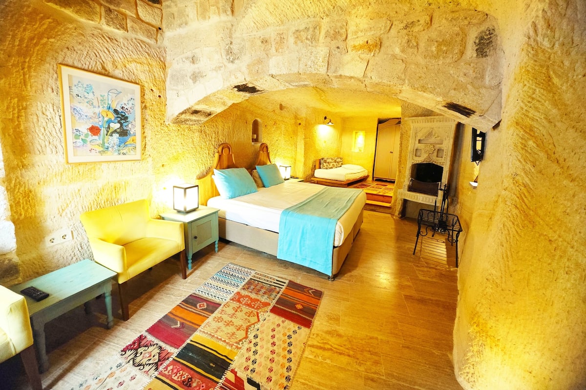 Un dormitorio acogedor y rústico con una cama grande, un sofá, una mesita y una chimenea.