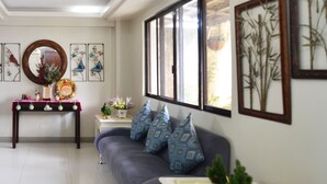 A living room with a sofa, a coffee table, and a side table with decorative items. - The Windy Ridge Inn (Tagaytay)