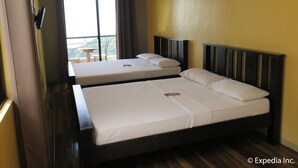 A hotel room with two beds, a balcony with a table and chairs, and a view of the outdoors. - The Windy Ridge Inn (Tagaytay)