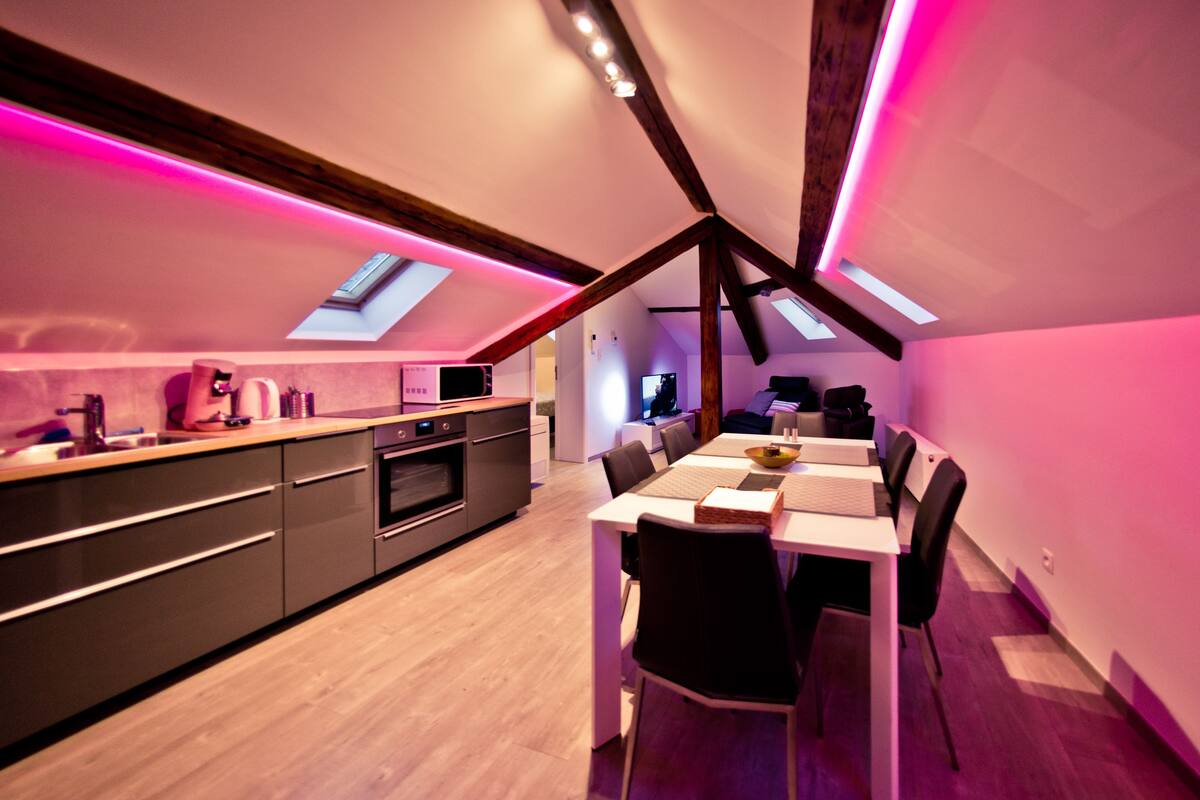 A modern kitchen with a dining area, skylights, and a wooden ceiling structure.