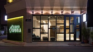 A modern hotel entrance with a well-lit facade, large glass doors, and a visible interior with seating and a statue. - MUNA Hostel (Hualien City)