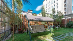 A patio area with a swing set, a covered seating area, and a stone pathway. - MUNA Hostel (Hualien City)