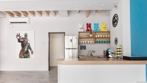 A modern kitchen with a wooden countertop, a refrigerator, and a wall-mounted shelf with cups and a clock. - MUNA Hostel (Hualien City)