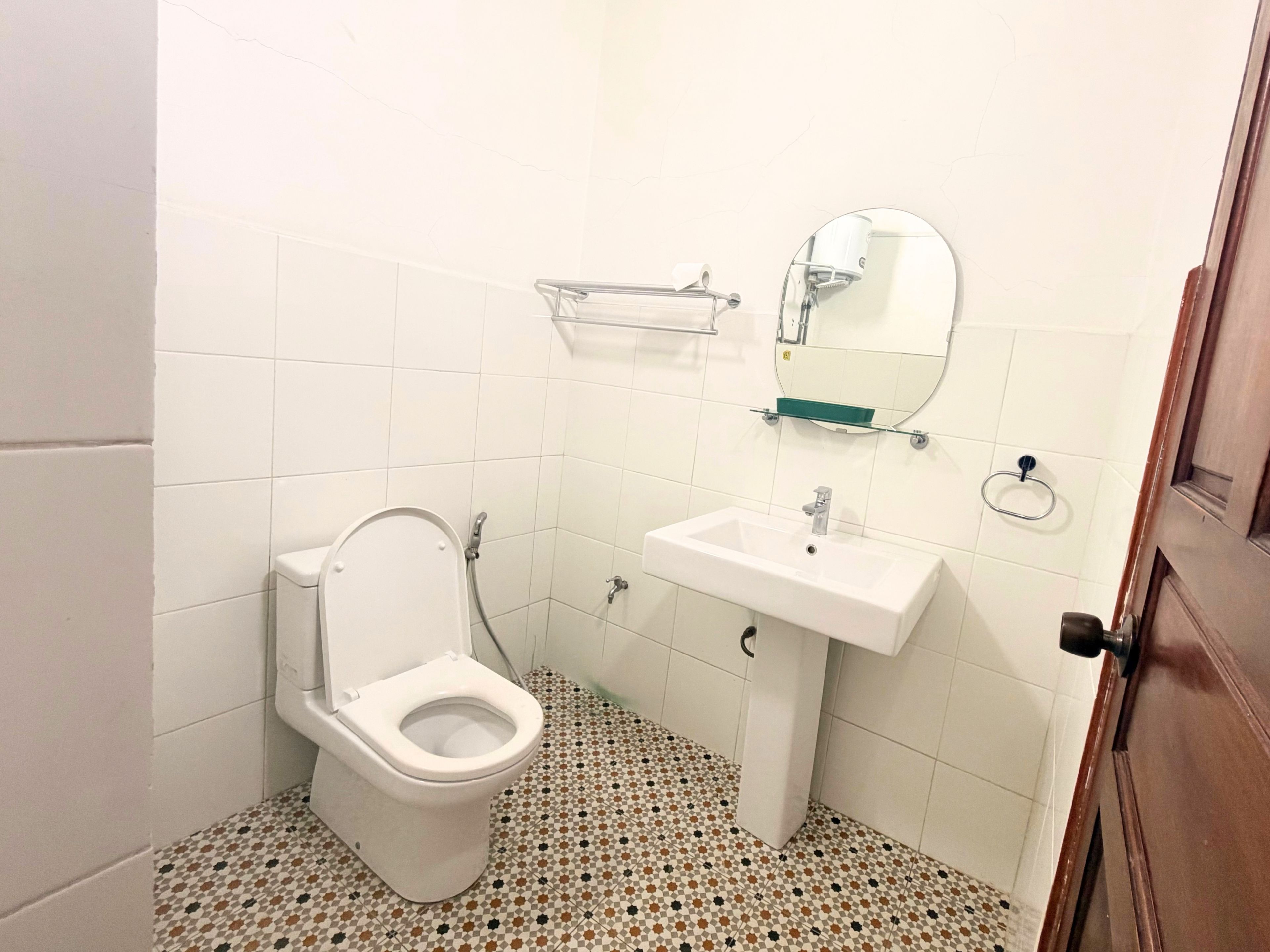 A bathroom with a toilet, sink, and mirror.