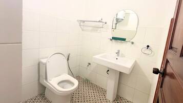 A bathroom with a toilet, sink, and mirror.