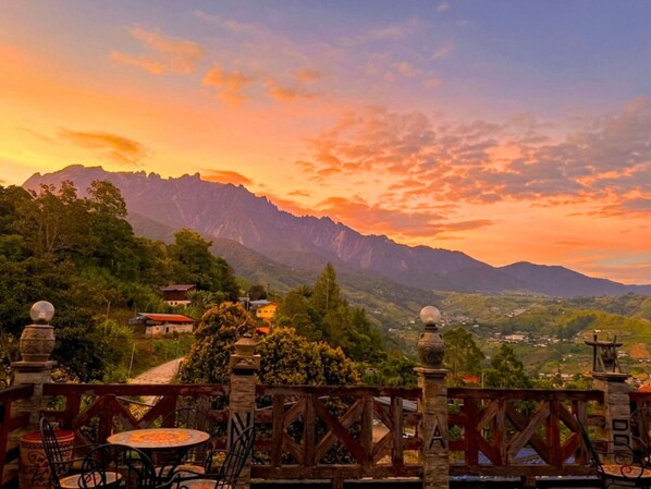 A terrace with a view of mountains and a sunset. - Nabalu Kundasang Lodge (Ranau)