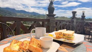A table with toast, a cup of coffee, and a sandwich, set against a scenic mountain backdrop.