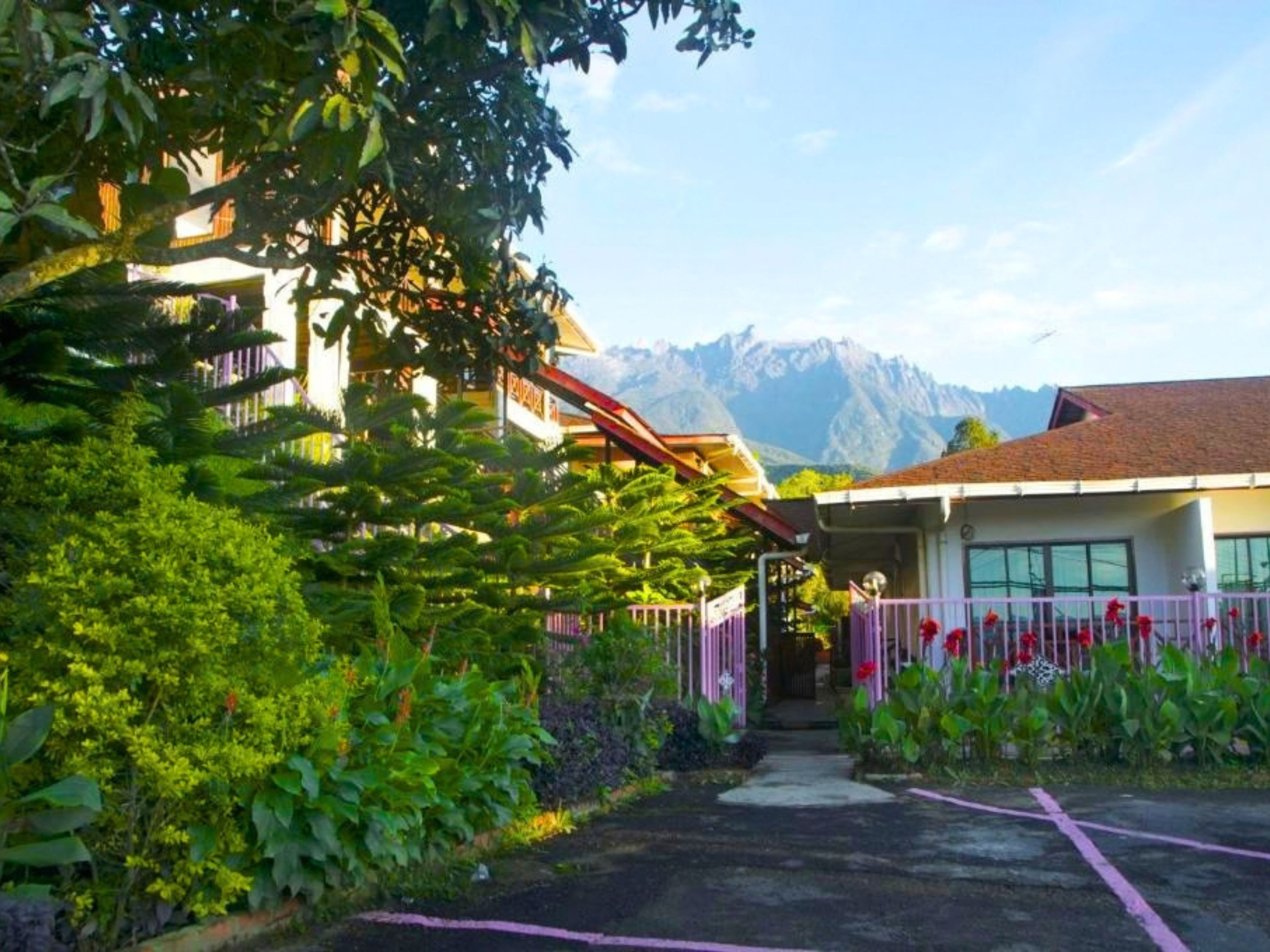 Entrada de hotel con vista a la montaña, un paseo techado y un estacionamiento.
