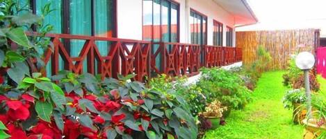 A hotel with a fenced garden area, potted plants, and a well-maintained lawn.
