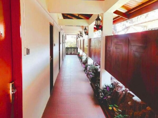 A corridor with a tiled floor, wooden doors, and a row of potted plants. - Nabalu Kundasang Lodge (Ranau)