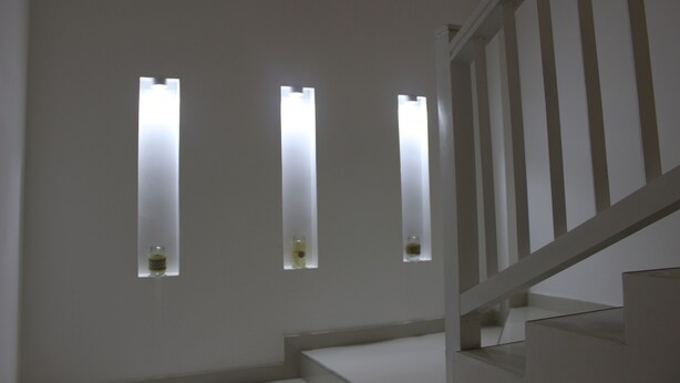 A staircase with a white railing and three rectangular windows with light fixtures. - Heaven By O (Unawatuna)