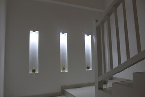 A staircase with a white railing and three rectangular windows with light fixtures. - Heaven By O (Unawatuna)