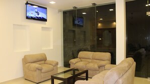 A modern living room with three beige sofas, a glass coffee table, and a flat-screen TV mounted on the wall. - Heaven By O (Unawatuna)