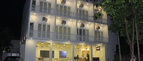 A multi-story hotel with balconies, air conditioning units, and a reception area.