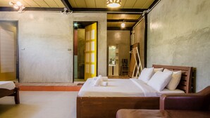 A bedroom with a large bed, a wooden headboard, and a brown leather sofa.