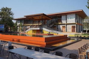 A two-story building with a swimming pool and outdoor seating area. - Riverpool Resort (Kanchanaburi)