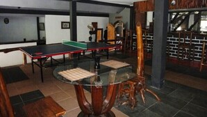 Une table de ping-pong, une table en verre avec un set de table en fibres tressées, et une chaise en bois au design original.