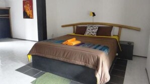 Une chambre à coucher avec un lit, une table de chevet, une lampe et une affiche accrochée au mur.