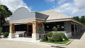A two-story building with a covered patio area, a tiled roof, and a row of windows. - Bypass and Resort (Kanchanaburi)