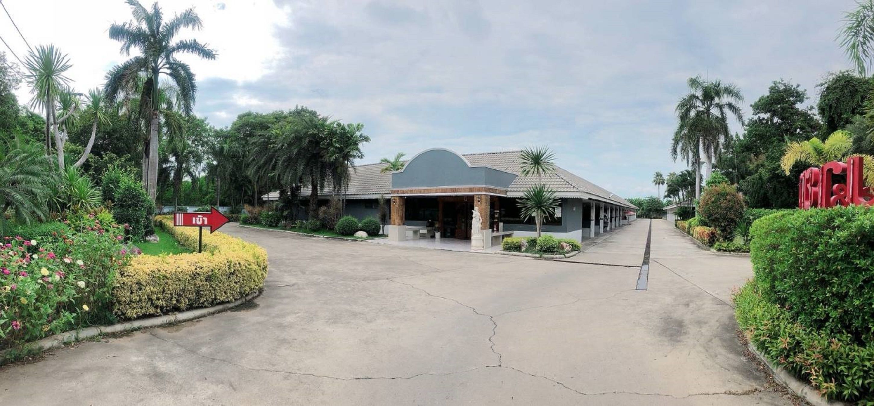 A hotel entrance with a covered walkway, palm trees, and a sign indicating a 101 room number.
