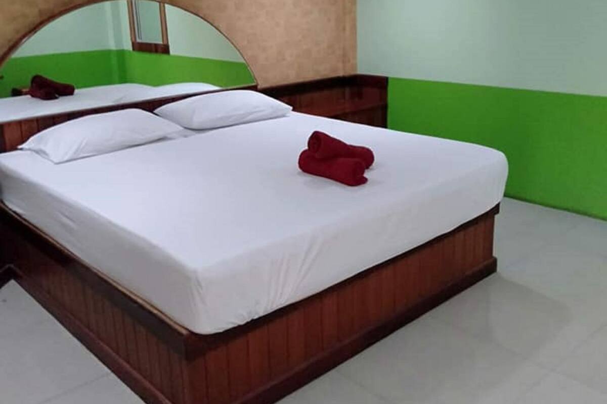 A hotel room with a large bed, a mirror, and an air conditioning unit on the wall.