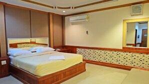 A hotel room with a wooden bed, a large mirror, an air conditioning unit, and a patterned wall. - Bypass and Resort (Kanchanaburi)