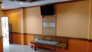 A room with a wooden bench, a television mounted on the wall, and a bulletin board with notices. - Bypass and Resort (Kanchanaburi)