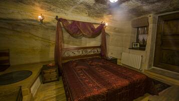 Un dormitorio con una cama de madera, una mesita de noche, una lámpara de pared y una ventana con cortina.