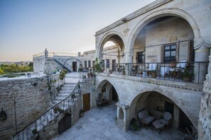Un patio con arquitectura de piedra, una escalera y mobiliario para exteriores.