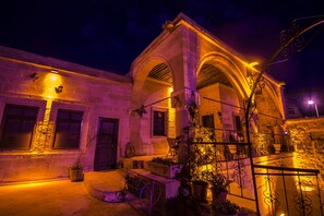 A historic building with arched windows and a stone facade, illuminated by warm lighting. - Assiana Cave House (Ürgüp)
