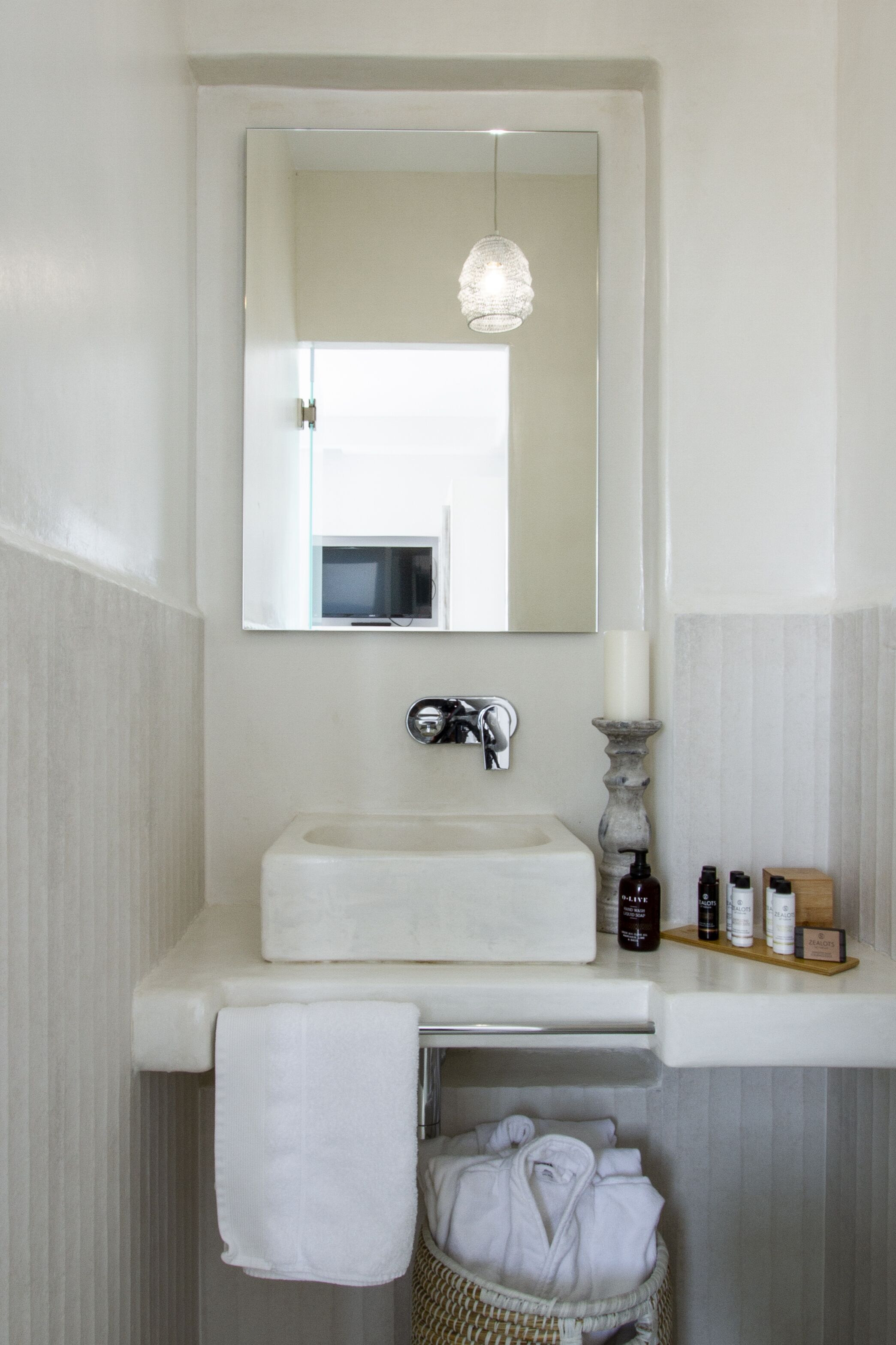 A bathroom with a white sink, mirror, and hanging light fixture.