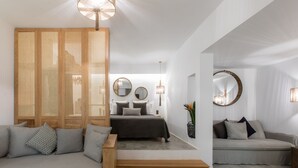 Et moderne soveværelse med en seng, to sofaer, en træbænk og et stort spejl.