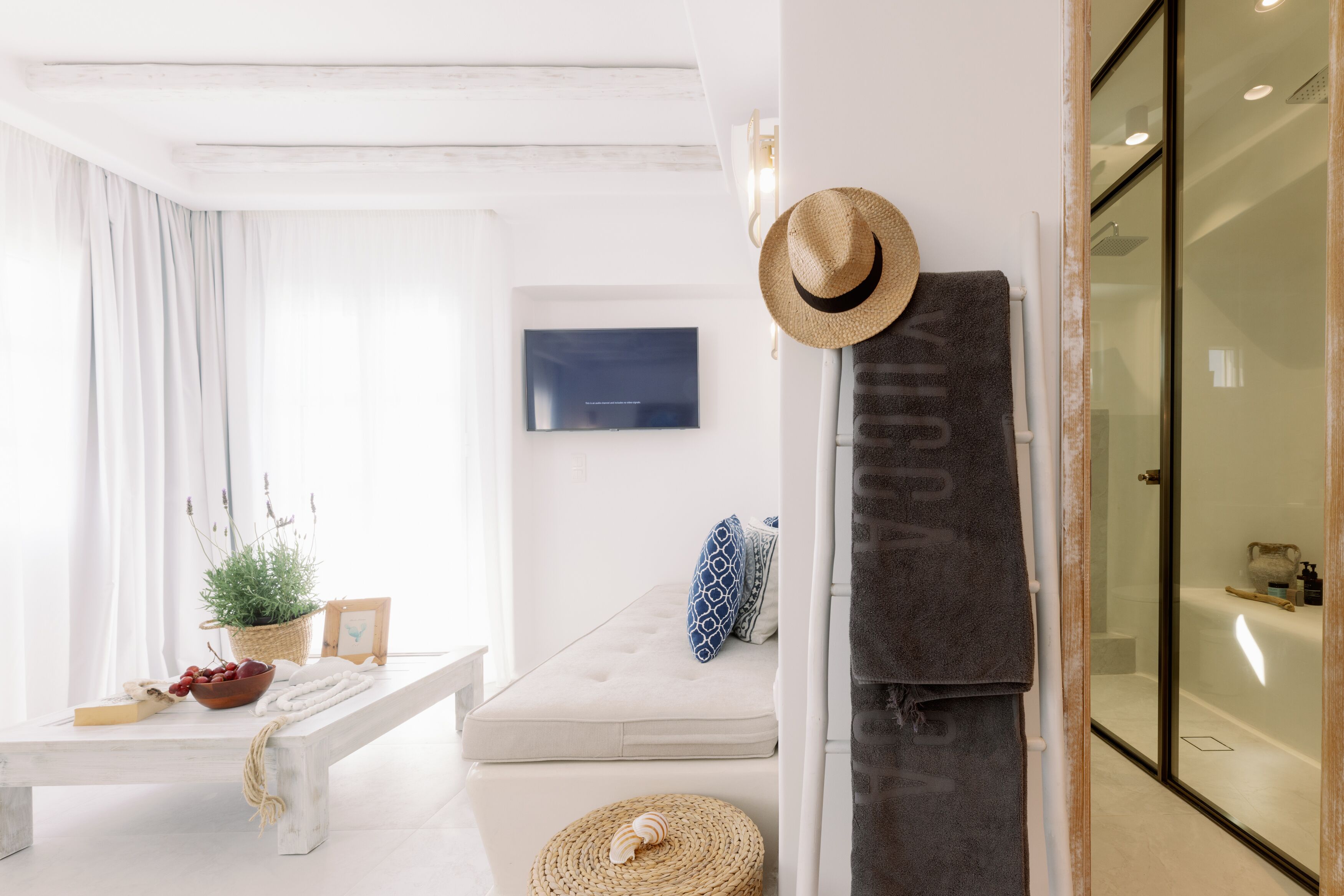 A modern living room with a sofa, a bench, a TV, a basket with plants, and a wall-mounted hat.