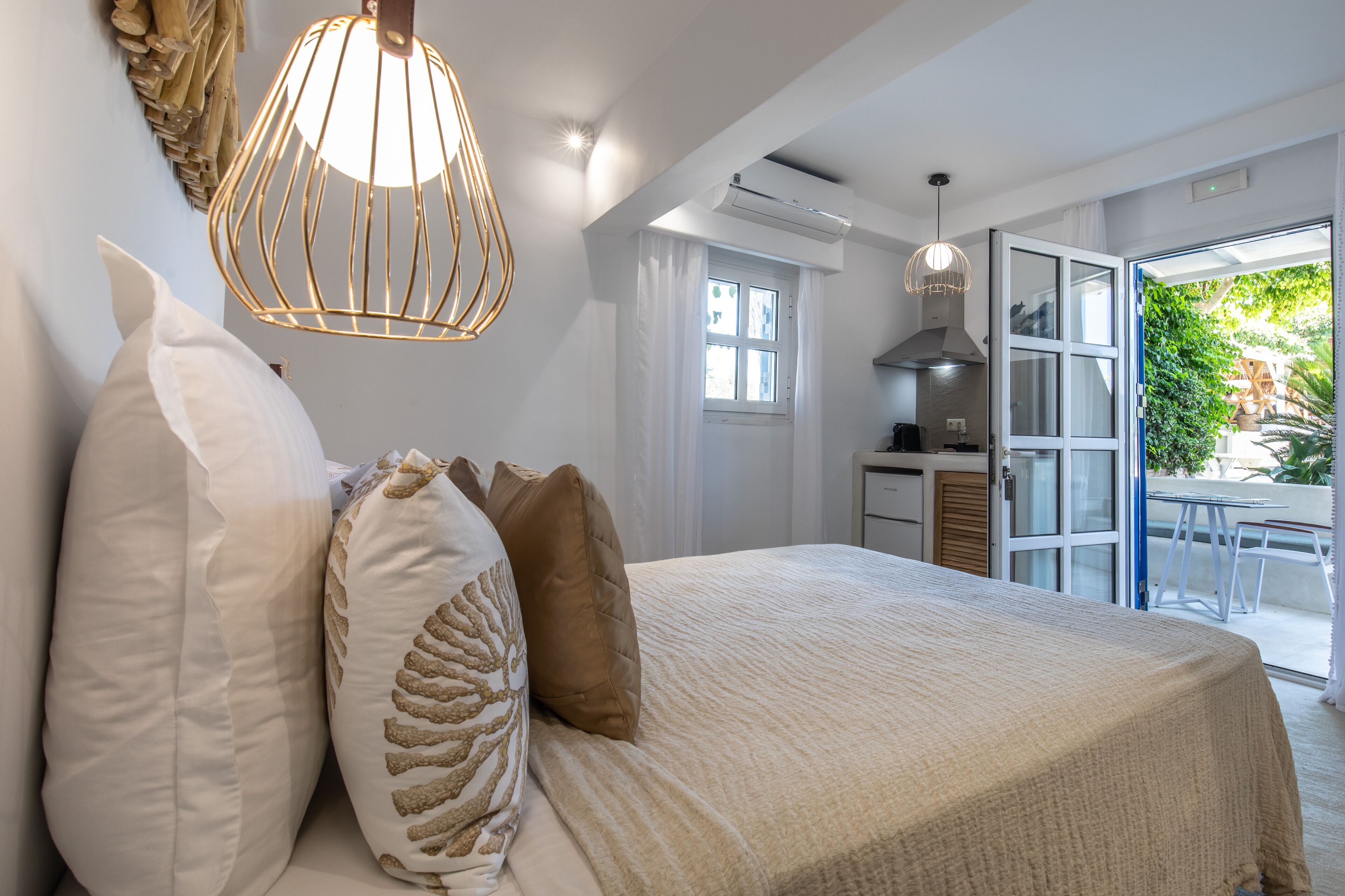 Ein Schlafzimmer mit einem großen Bett, einer Hängeleuchte und Blick ins Freie.