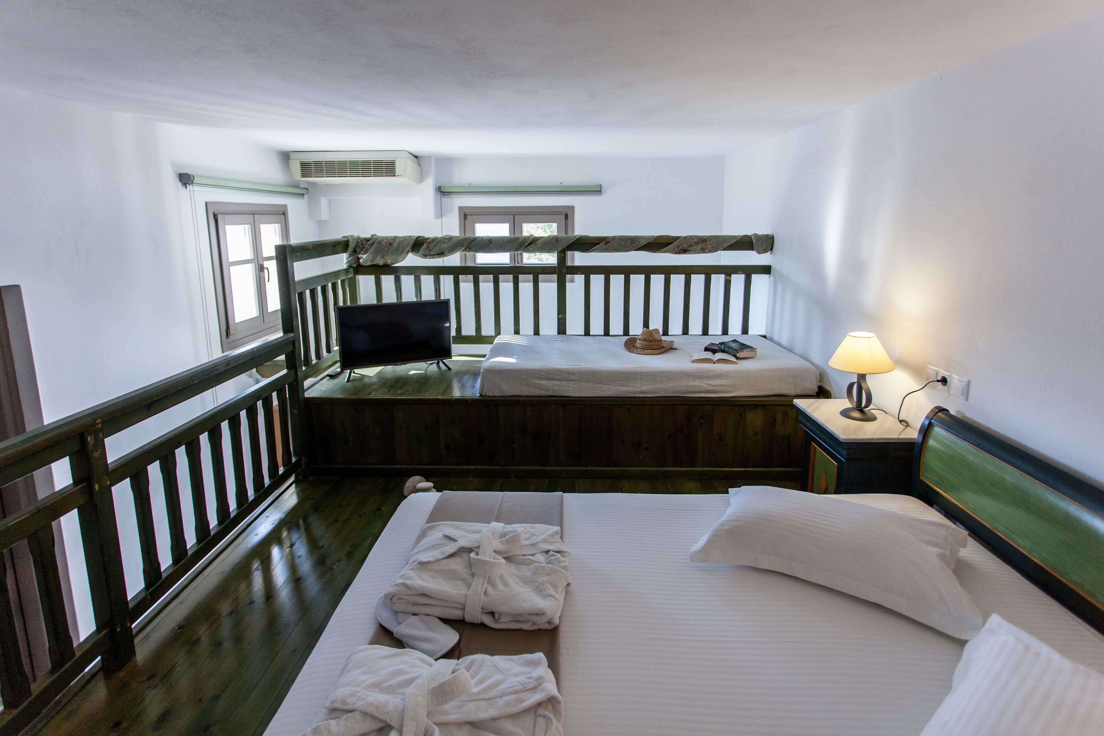 A room with two beds, a television, and a lamp.