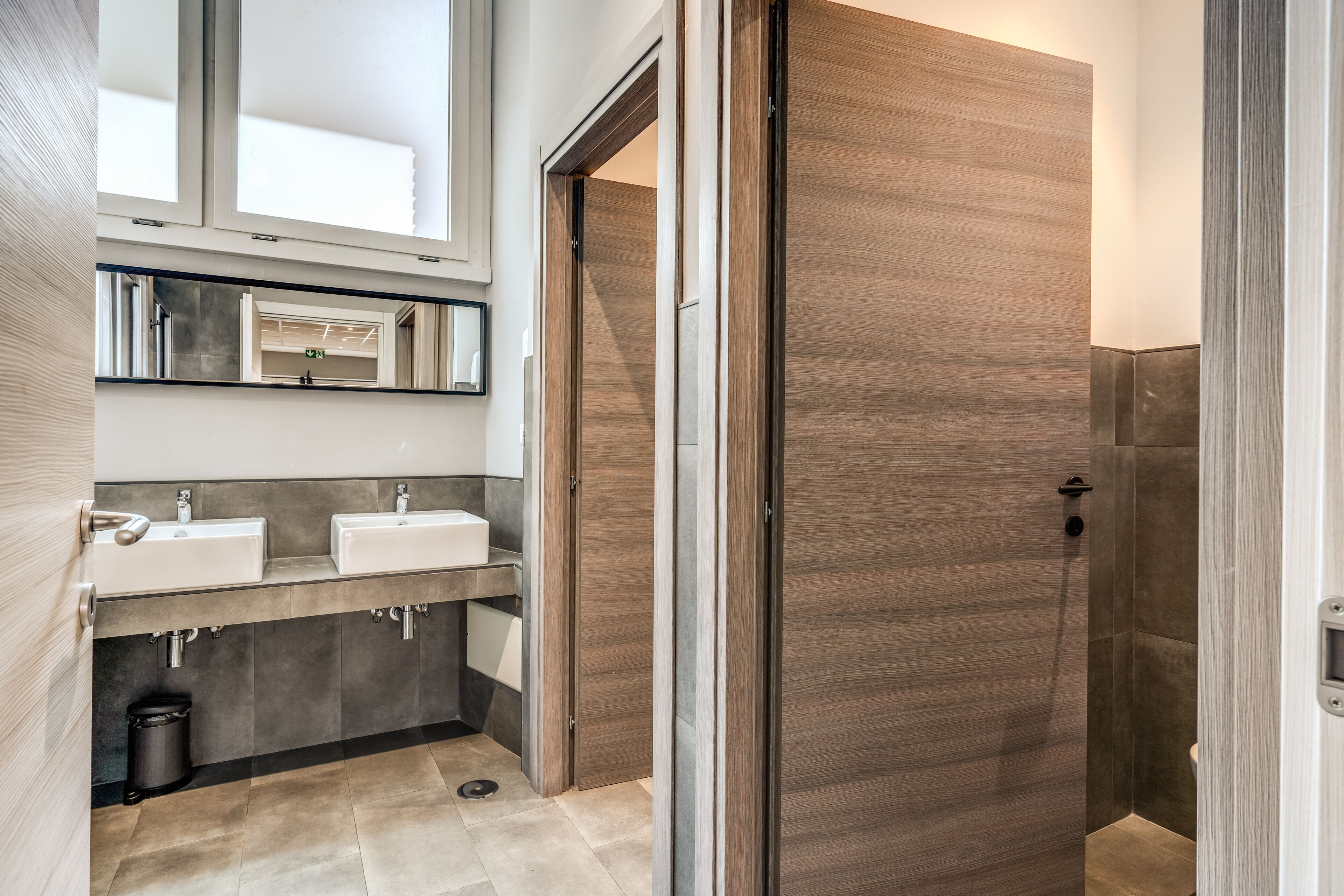 A modern bathroom with two sinks, a mirror, and a shower area.