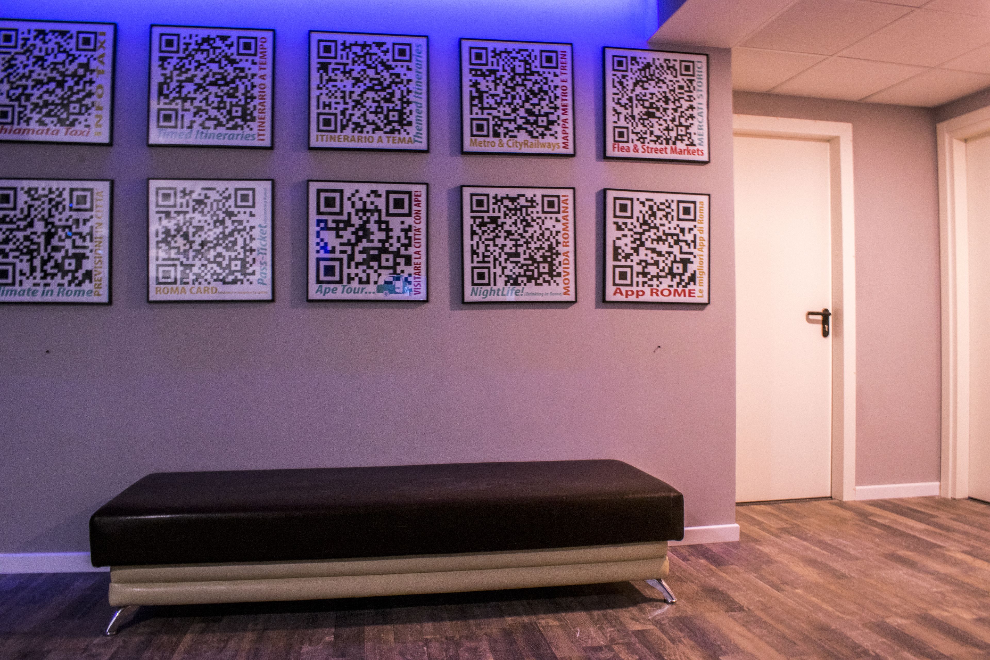 A room with a bench and a wall displaying QR codes for various services.