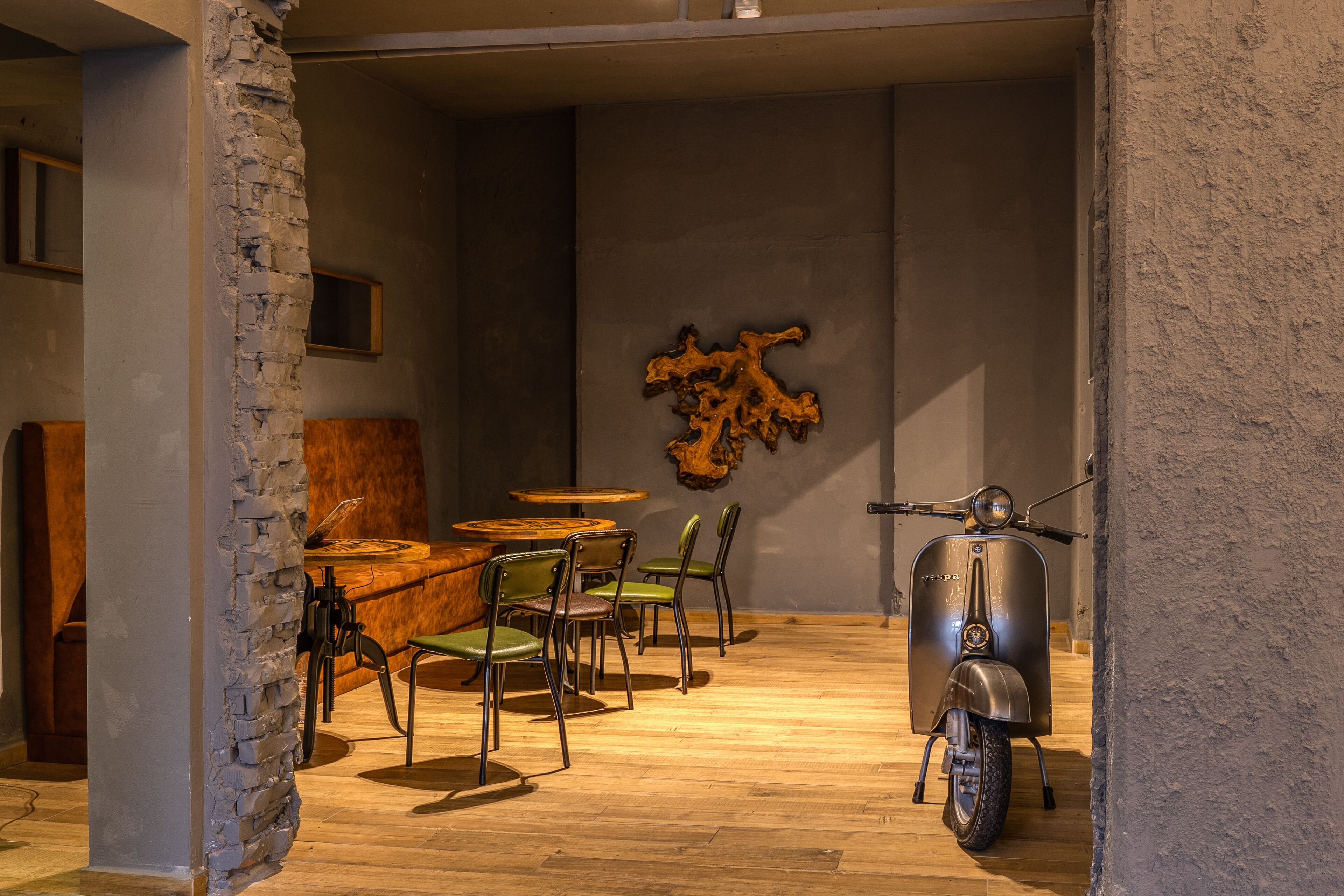 Un comedor con una mesa y sillas de madera, una moto y una obra de arte colgada en la pared.
