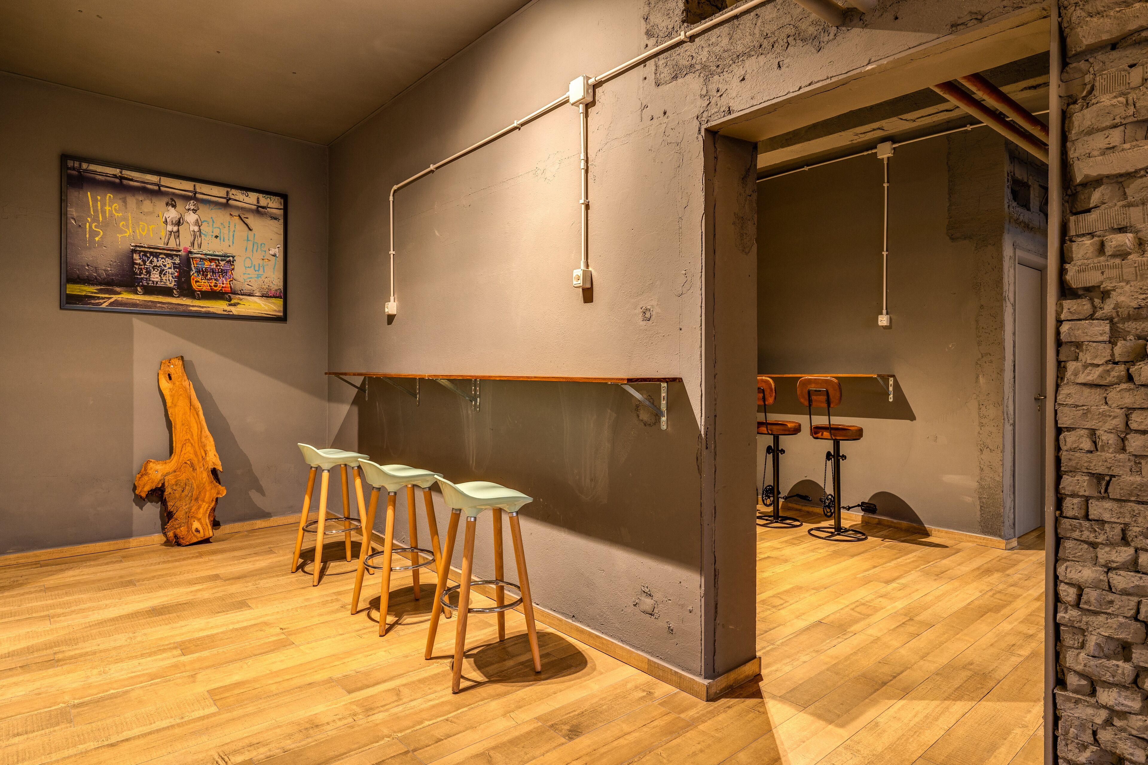 Una zona de bar con taburetes, una barra de madera y un mural en la pared.