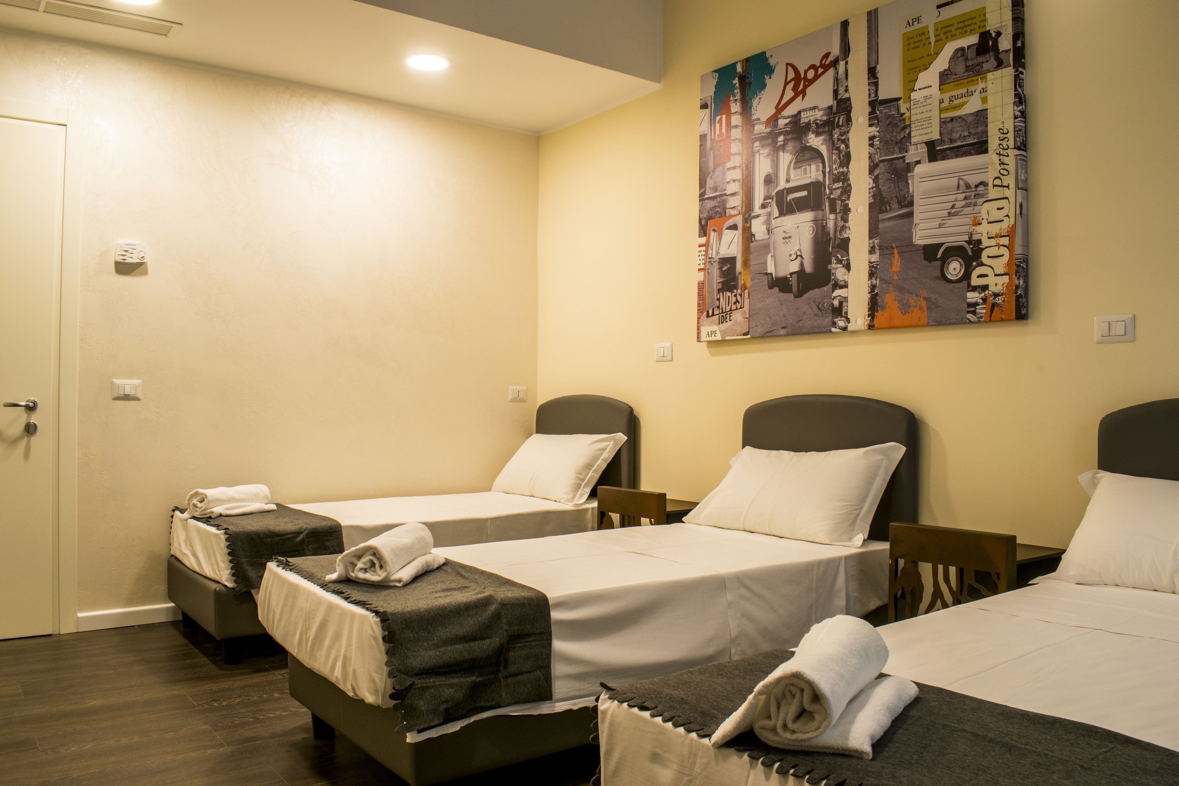 A hotel room with two single beds, a small table, and a chair.