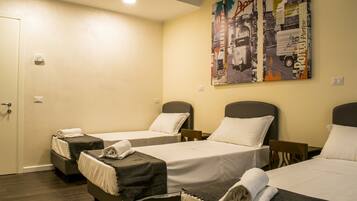A hotel room with two single beds, a small table, and a chair.