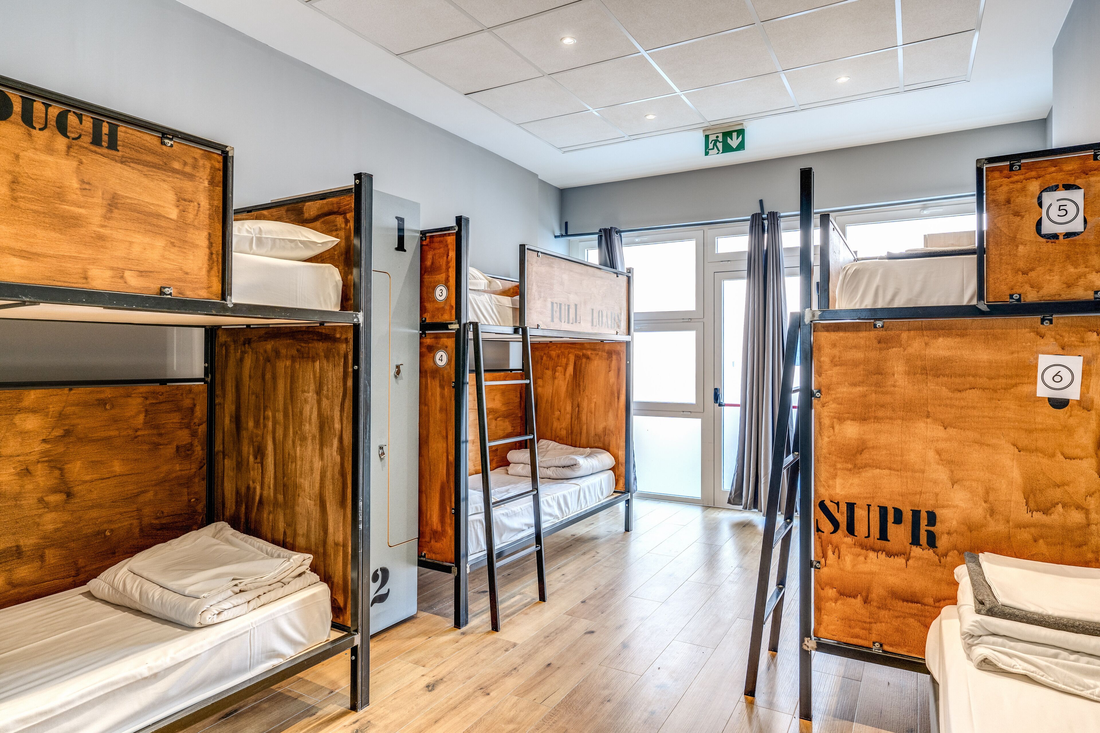 Una habitación de hotel con literas, cabeceros de madera y vistas al exterior.