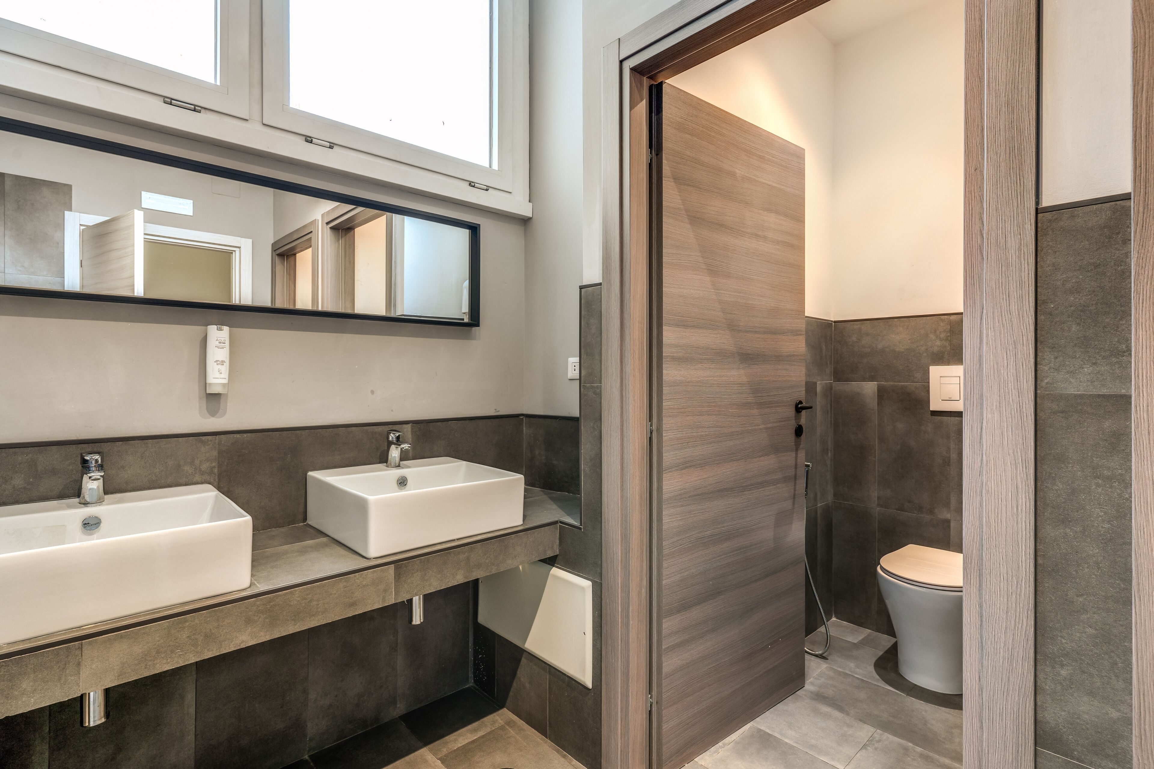 Ein modernes Badezimmer mit zwei Waschbecken, einem Spiegel und einer Duschkabine.