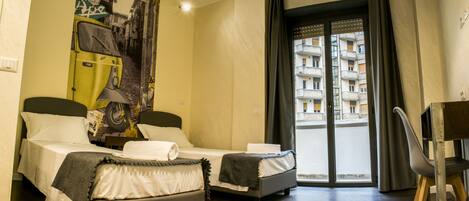 Ein Hotelzimmer mit zwei Betten, Blick auf ein Gebäude durch eine Glastür und einem Sessel.