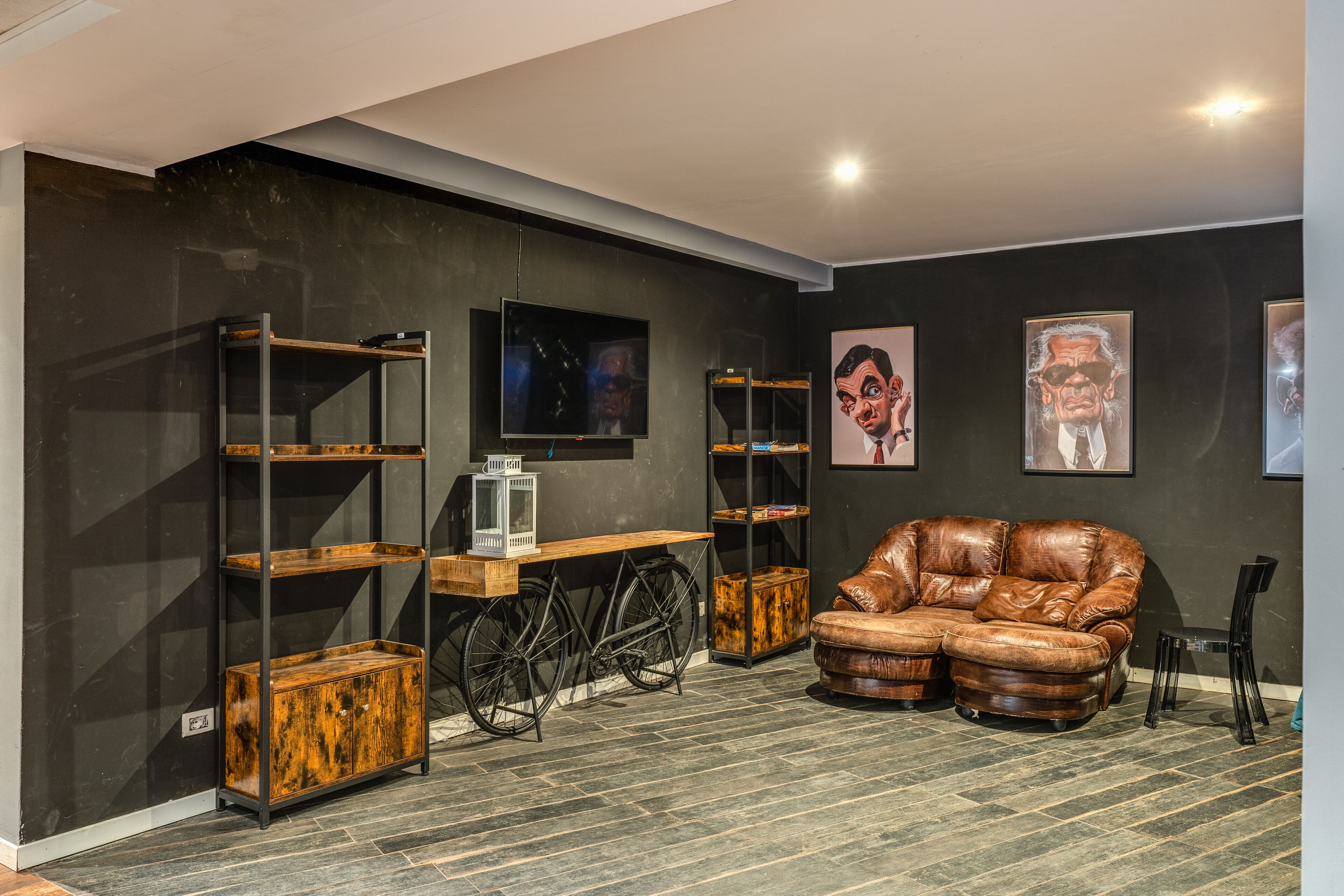 A modern living room with a leather sofa, wooden shelves, a bicycle, and artwork on the walls.