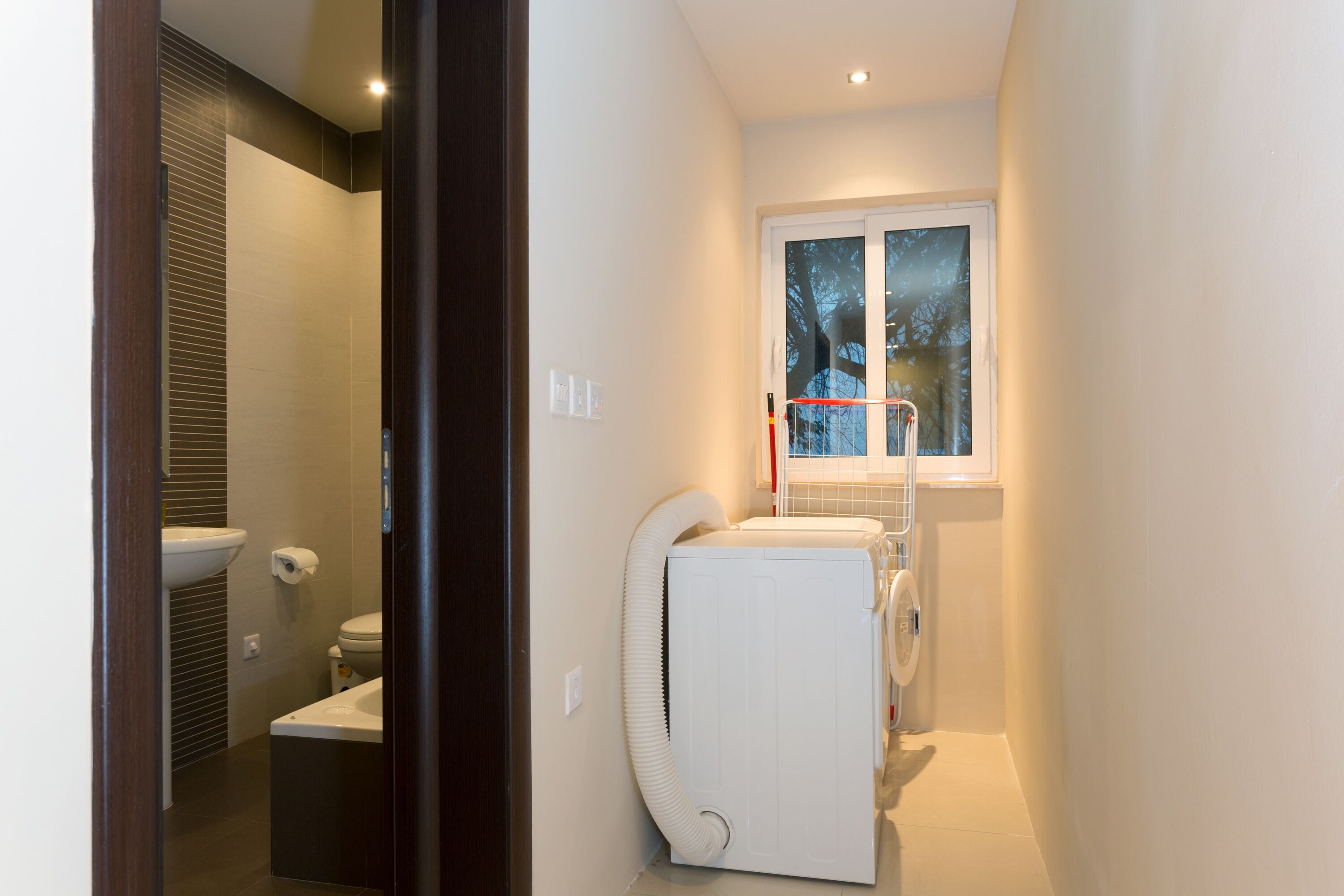 Een kleine badkamer met toilet, wastafel en een ingebouwde wasmachine.