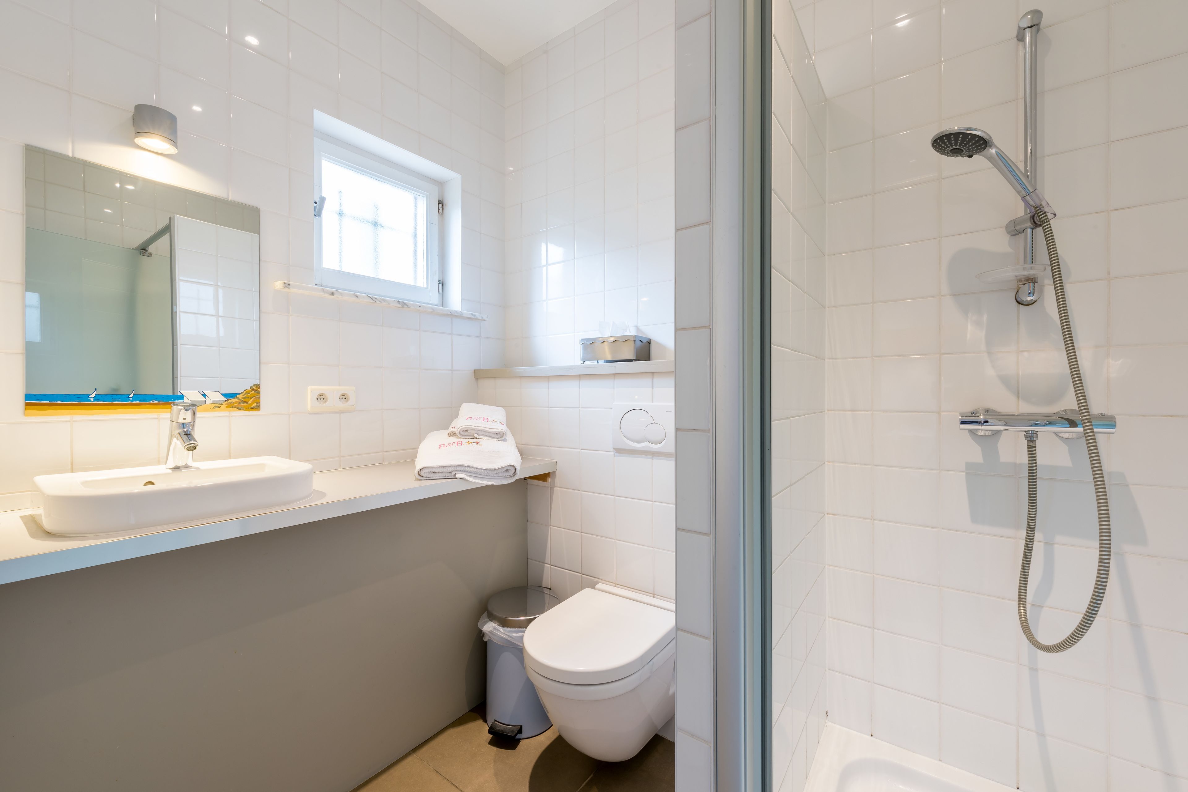 Un baño moderno con lavamanos, inodoro y ducha blancos.